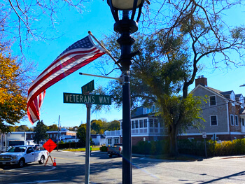 View of an intersection with a flag and Veterans Way street sign